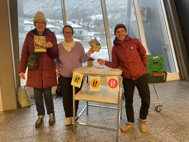 3 Personen an einem Stand am Unterschriften sammeln